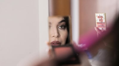 Eljammi Gozalli, beauty blogger and makeup artist is seen in the reflection of a mirror she is holding. Reem Mohammed / The National