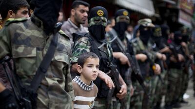 A boy stands between Palestinian militants from Islamic Jihad's armed wing, the Al Quds Brigades, during the funeral of their three comrades in Khan Yunis in the southern Gaza Strip, who were killed in an Israeli airstrike on March 11. The Israeli army confirmed the strike, saying the air force had targeted Islamic Jihad militants who had fired at troops. Mahmud Hams / AFP Photo