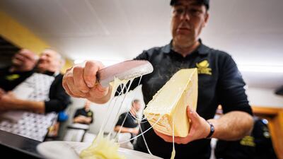 A "scaper" prepares a raclette during the first-ever Raclette World Championships featuring local and international raclette cheeses, in Morgins, on October 28, 2023. Up in the Swiss Alps, the air hangs thick with the funk of hot cheese as the planet's best melt away the competition at the inaugural Raclette World Championships. The Swiss native dish dates back centuries to a time when mountain herdsmen would heat their cheese on an open fire and scrape off the melted part to keep them going. (Photo by VALENTIN FLAURAUD / AFP)