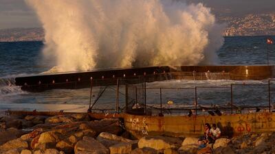 A couple drinks coffee as waves smash along the Beirut coastline, Lebanon. AP Photo