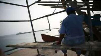 A man on Delma Island repaints a fishing boat.