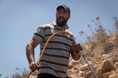 Sari Aldakrouny, a farmer and volunteer firefighter drenches the perimeter of the blaze to ensure the fire doesn't reignite after the team leaves. Matt Kynaston for The National.