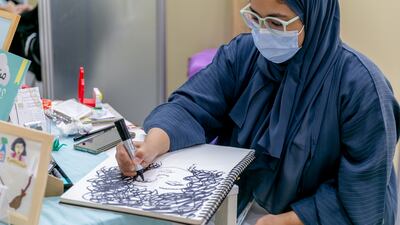 Artist Sally Alhashmi working at the illustrators' corner at the fair
