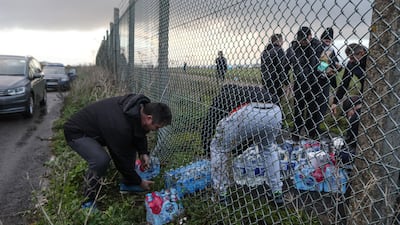A volunteer passes cartons of bottled water under a perimeter fence to truck drivers at Manston airport in Manston, U.K. Routes to Dover, Britain's busiest cross-channel port, have been choked for days after France shut its border with Britain, blaming an outbreak of a novel strain of the coronavirus. Bloomberg