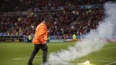 A steward removes a flare from the pitch. Pavel Golovkin / AP Photo