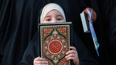 A girl holds the Quran at a July 2 rally in Basra, Iraq, protesting against the burning of the holy book in Sweden. AP