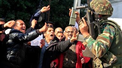 Protesters and soldiers during a demonstration in the centre of Tunis yesterday. Tunisian security forces used water cannon and tear gas and fired shots in the air as demonstrators took to the streets demanding that the ruling party give up power.