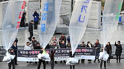 South Korea is allowing citizens to send messages of condolence to the North but not all residents are embracing the gesture, with some anti-North Korea protesters, above, yesterday releasing balloons containing leaflets denouncing Kim Jong-il at Imjingak peace park in Paju.