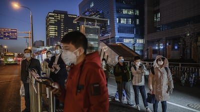 Chinese commuters wear protective masks as they line up in a staggered formation while waiting for a bus at the end of the work day in Beijing. Getty Images