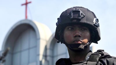 An Indonesian police officer stands guard near a bombed church in Surabaya, Indonesia. Robert Rizky / EPA
