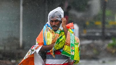 A pedestrian improvises rainwear with plastic bags and scraps in the city of Amreli, Gujurat state, western India. AFP