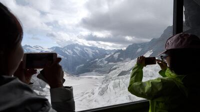 Chinese tourists use their mobile phone to picture the Ischmeer glacier form a window at the Eismeer railway station, 3159 meters high, during their trip at the Jungfraujoch high in the Swiss Alps. Fabrice Coffrini/AFP