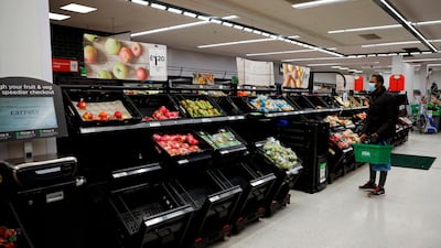 A shopper wearing a face mask looks at empty fruit and vegetable troughs inside an ASDA supermarket. AFP