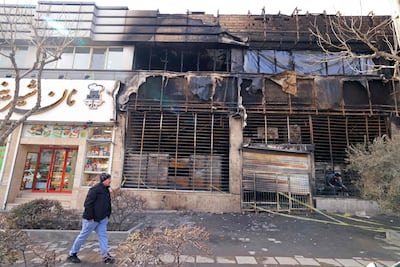 A pedestrian passes a Saderat Bank building that was burned out during protests in Tehran. AFP