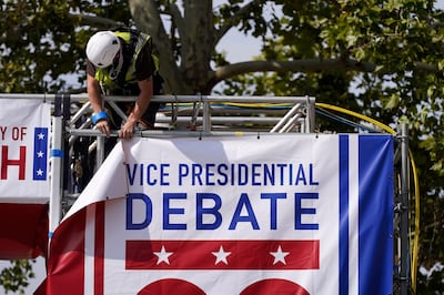 A worker hangs a banner as preparations take place for the vice-presidential debate outside Kingsbury Hall at the University of Utah on Monday. AP Photo