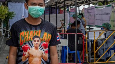 In this Thursday, March 19, 2020, photo, a Muay Thai boxing fighter stands in front of makeshift screening facility outside Rajadamnern boxing stadium in Bangkok, Thailand. AP