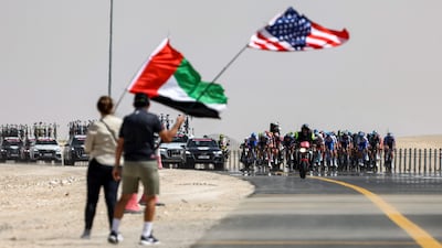 Race fans wave flags as the peloton approaches. AFP