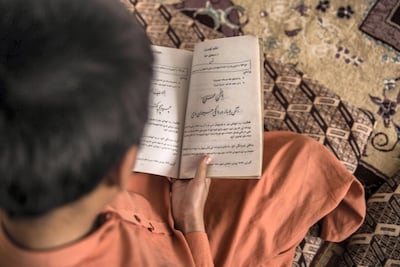 Adeel, 11, reads one of his school books at home in his living room. He is originally from Pakistan, but lives in Afghanistan, where his father works is a Taliban fighter. Stefanie Glinski for The National