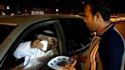 Ahmed Ali Alyfei has tea delivered to his car after beeping his horn in Al Reehan in the capital.