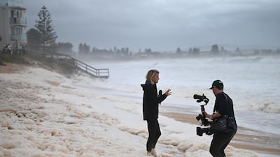 A news team films sea foam brought in by waves after heavy rain and storms at Collaroy in Sydney. EPA