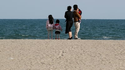 A family takes a moment as they visit Arahama Beach in Sendai, Miyagi Prefecture, Japan, on March 11, 2018. Kimimasa Mayama / EPA