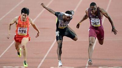 China's Su Bingtian, leftm crosses the finish line to win gold ahead of Qatar's Samuel Adelebari Francis (R) in second and a lunging Barakat Al Harthi of Oman, centre.