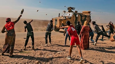 Syrians throw stones towards Turkish military vehicles during a Turkish-Russian army patrol near the town of Darbasiyah in Syria's northeastern Hasakeh province along the Syria-Turkey border. AFP