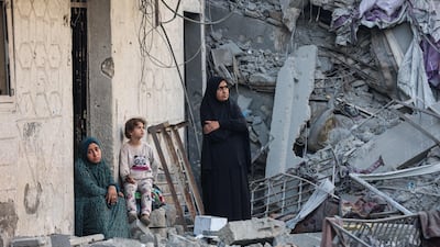 Women and a child sit amid the rubble of a house in Gaza city in October. AFP
