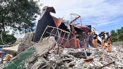 Rescuers search for three people in the building in Bogo City. AFP