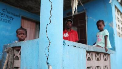 A man and two children stand on the porch of their home after it was damaged in an earthquake in Port-de-Paix, Haiti. Reuters