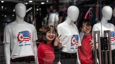 Shop assistants react to the camera after having their photographs taken by a friend next to T-shirts celebrating the forthcoming North Korea-USA summit. Getty Images