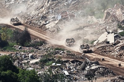 Israeli military vehicles drive past destroyed buildings on the Lebanese side of the border. EPA