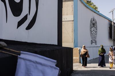Children stand outside the former US embassy in Kabul where the banner of the Taliban has replaced previous murals. Stefanie Glinski for The National