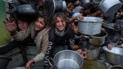 Palestinian women and girls struggle to reach for food at a distribution centre in Khan Younis, Gaza Strip. AP