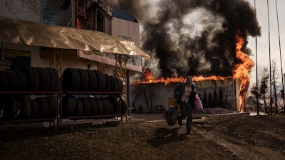 A man recovering items from a burning shop after a Russian attack in Kharkiv in March 2022