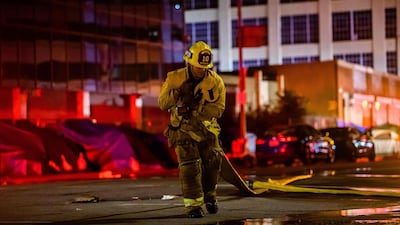 A firefighter drags a hose on San Pedro Street after a fire in a single-story commercial building sparked an explosion in the Toy District of downtown Los Angeles. AFP