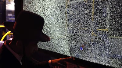 A security forces member examines what appears to be a bullet hole in a shattered window. AFP