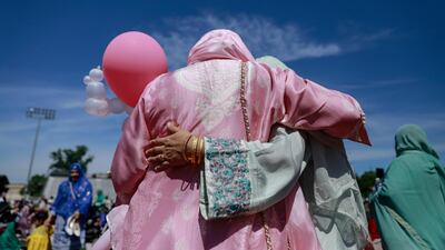 Two women embrace after performing Eid Al Fitr prayers on the Niles West High School football field in Skokie, Illinois.