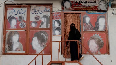 An Afghan woman enters a beauty salon where the adverts have been defaced, in Kabul. Reuters
