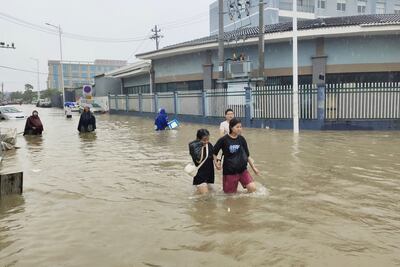 People wade through a flooded road in Dongqiao town of Ningbo, Zhejiang province, as Typhoon In-fa lashes the coastal regions in China July 25, 2021. REUTERS