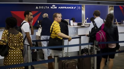 Travellers wait to check in for flights at the Delta Air Lines counter of LaGuardia Airport in New York. Victor Blue / Bloomberg