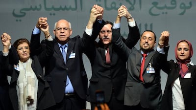 The head of Libya’s new national government, Fayez Al Sarraj, centre, celebrates with the deputy head of Libya’s House of Representatives, Mohamed Ali Shoeb, left, and the deputy president of General National Congress, Saleh Al Makhzoum, right, both of whom have now been disowned by their respective legislatures, after signing a deal on a unity government on December 17, 2015, in Skhirat, Morocco. Fadel Senna / AFP