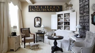 In the sitting room, a gold-lettered shop sign hangs on the wall adjacent to the English bus blind.