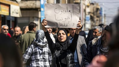 A woman holds a sign reading 'Alawites are our brothers and family' during a demonstration in March against sectarian violence. AFP