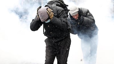Pro-European protesters cover their ears while running amidst smoke during clashes with riot police in Kiev. Vasily Fedosenko / Reuters