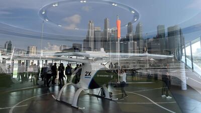 The city skyline with the prototype of Voloport launch pad are reflected on a glass panel while visitors view the Volocopter unmanned air taxi transport displayed ahead of the 26th Intelligent Transport Systems World Congress (ITSWC) in Singapore. AFP
