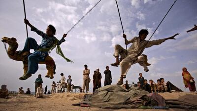 Pakistani children whose families fled from fighting ride a merry-go-round on the outskirts of Islamabad, Pakistan.