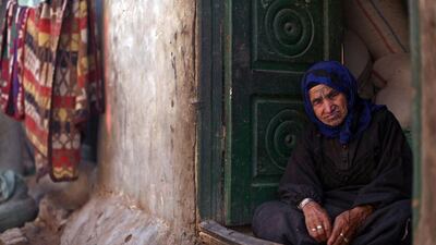 An elderly Palestinian refugee sits at the entrance of her house in Gezirat al-Fadel village.