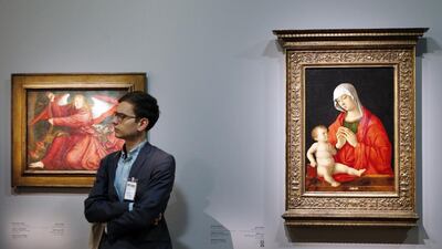A man stands next to two paintings, one by Giovanni Bellini entitled ‘The Virgin and the Child’ (Italy, approx 1480-85), right, and another by Bernard Strigel entitled ‘The Angel and the Incense burner’ (Germany, 1520). Francois Guillot/AFP