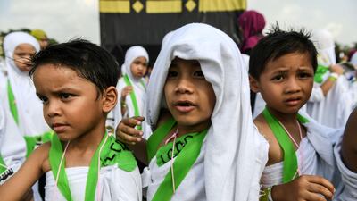 Ihram-clad Malaysian Muslim boys from the Little Caliphs kindergarten rest while circumambulating a mockup of the Kaaba.